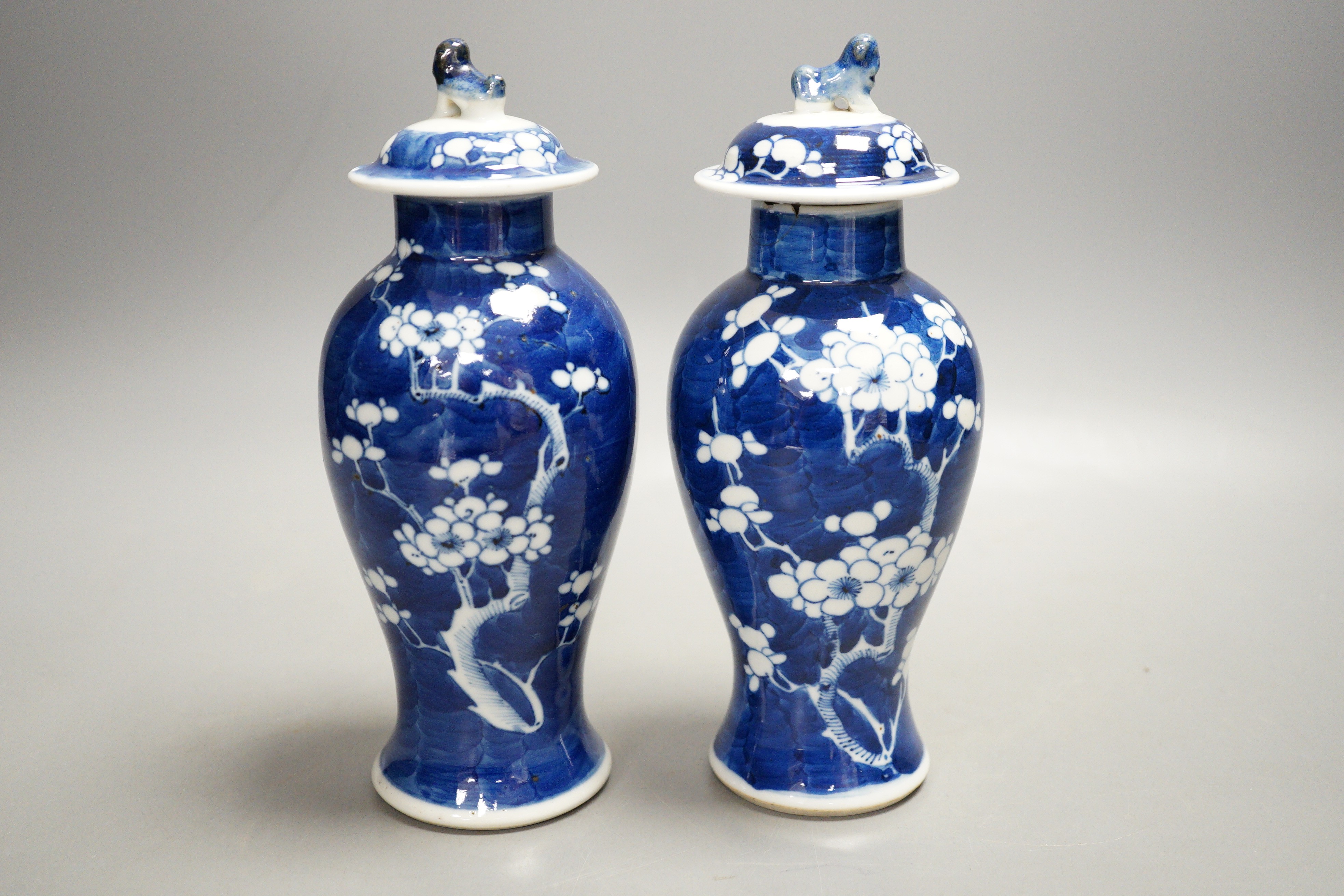 A pair of early 20th century Chinese blue and white ‘prunus’ vases and covers, 21cm